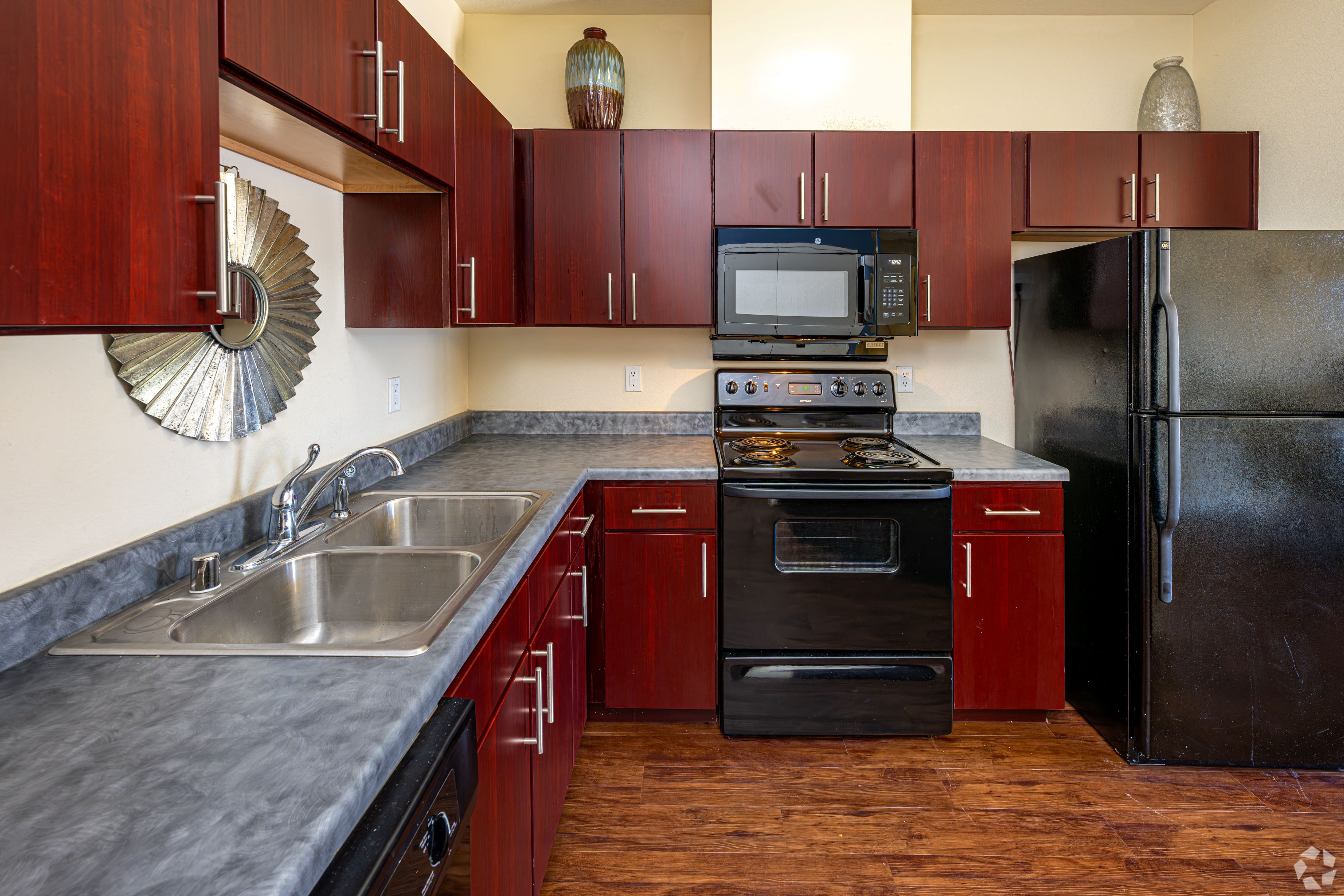 A kitchen with dark wood cabinets and a black refrigerator.